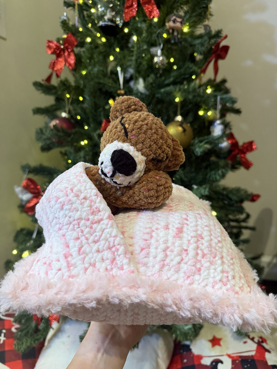 Brown crochet bear attached to a pink and white blanket.