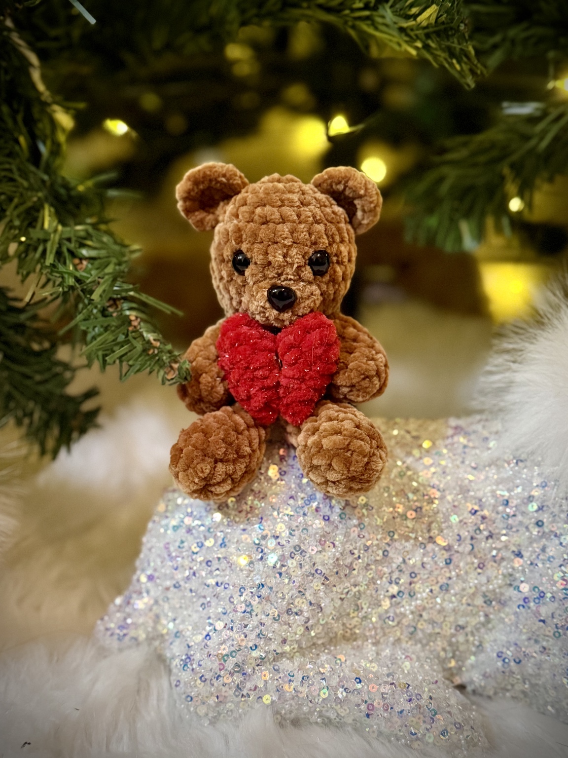 Small brown crochet teddy bear holding a red heart.