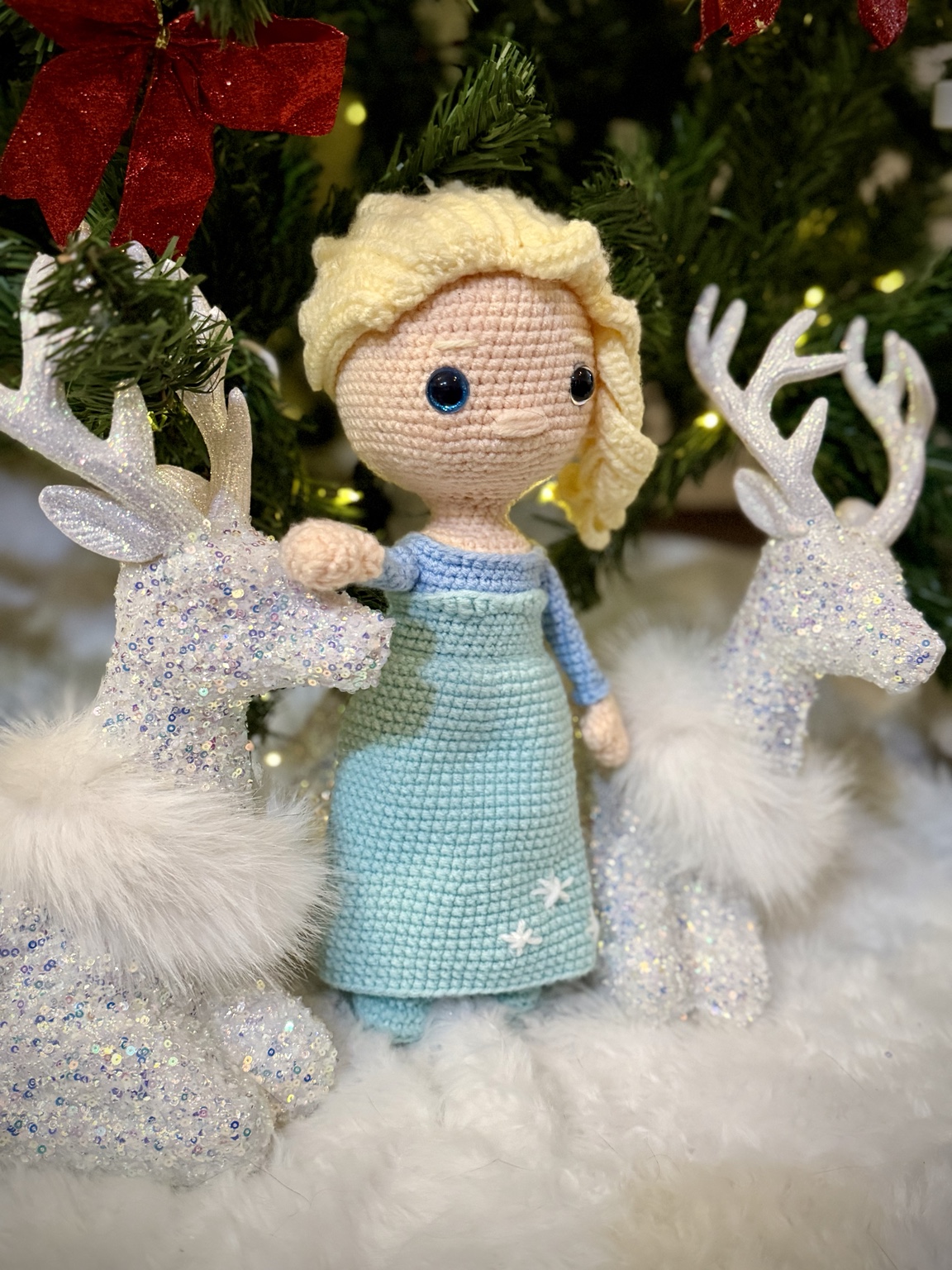Crochet princess doll with blonde hair and a blue dress, beside decorative reindeer.