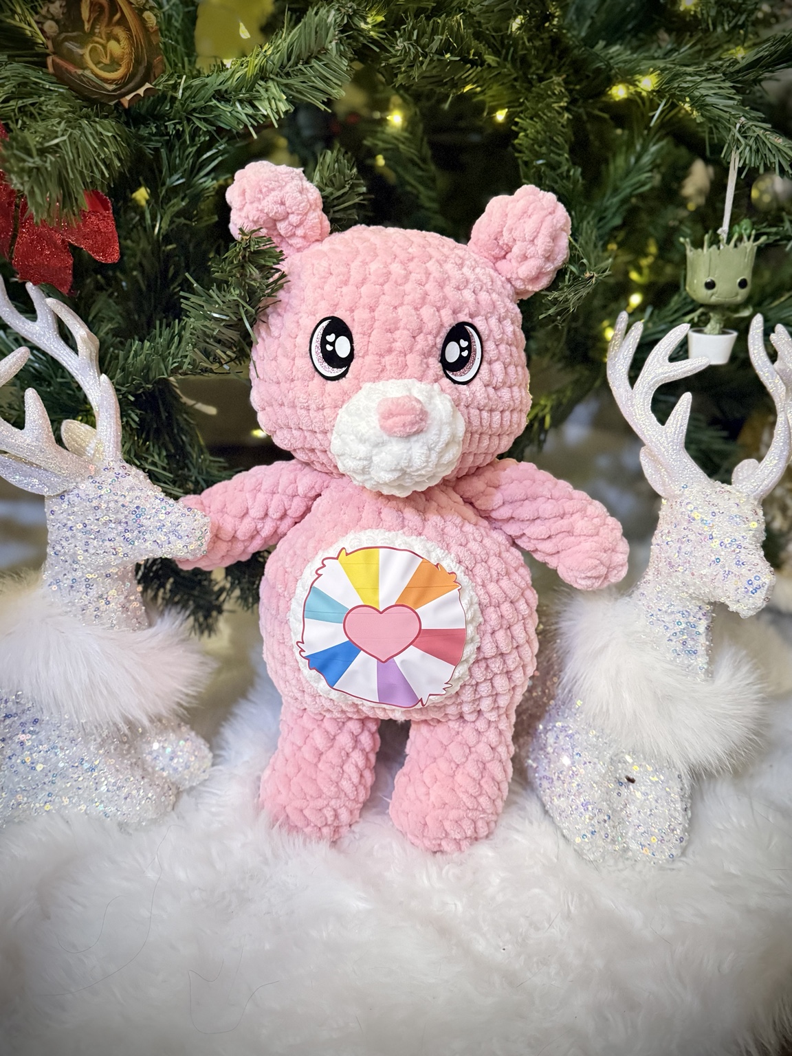 Pink crochet bear with a rainbow and heart on its belly.