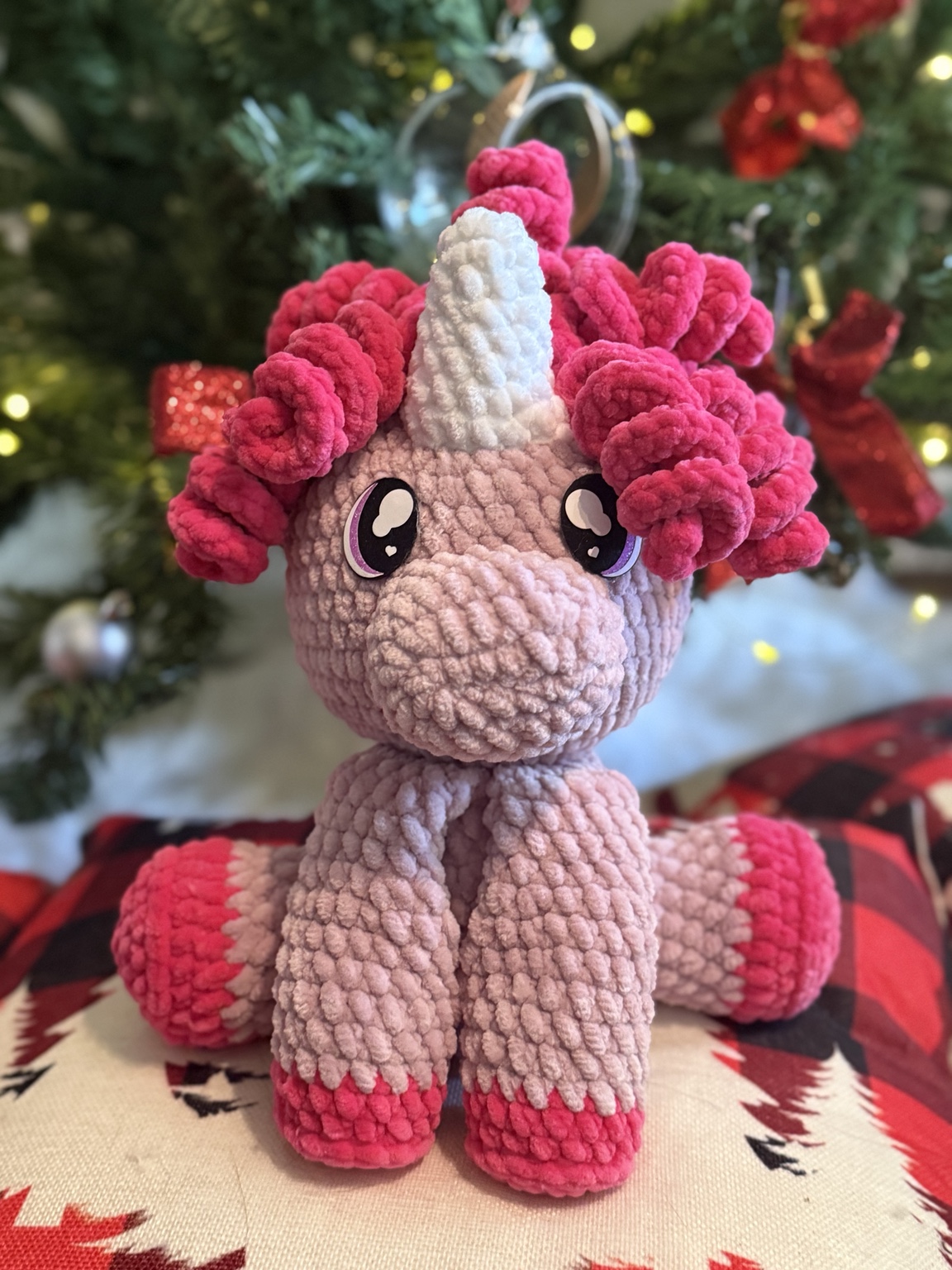 Pink crochet unicorn with a white horn and curly dark pink mane.