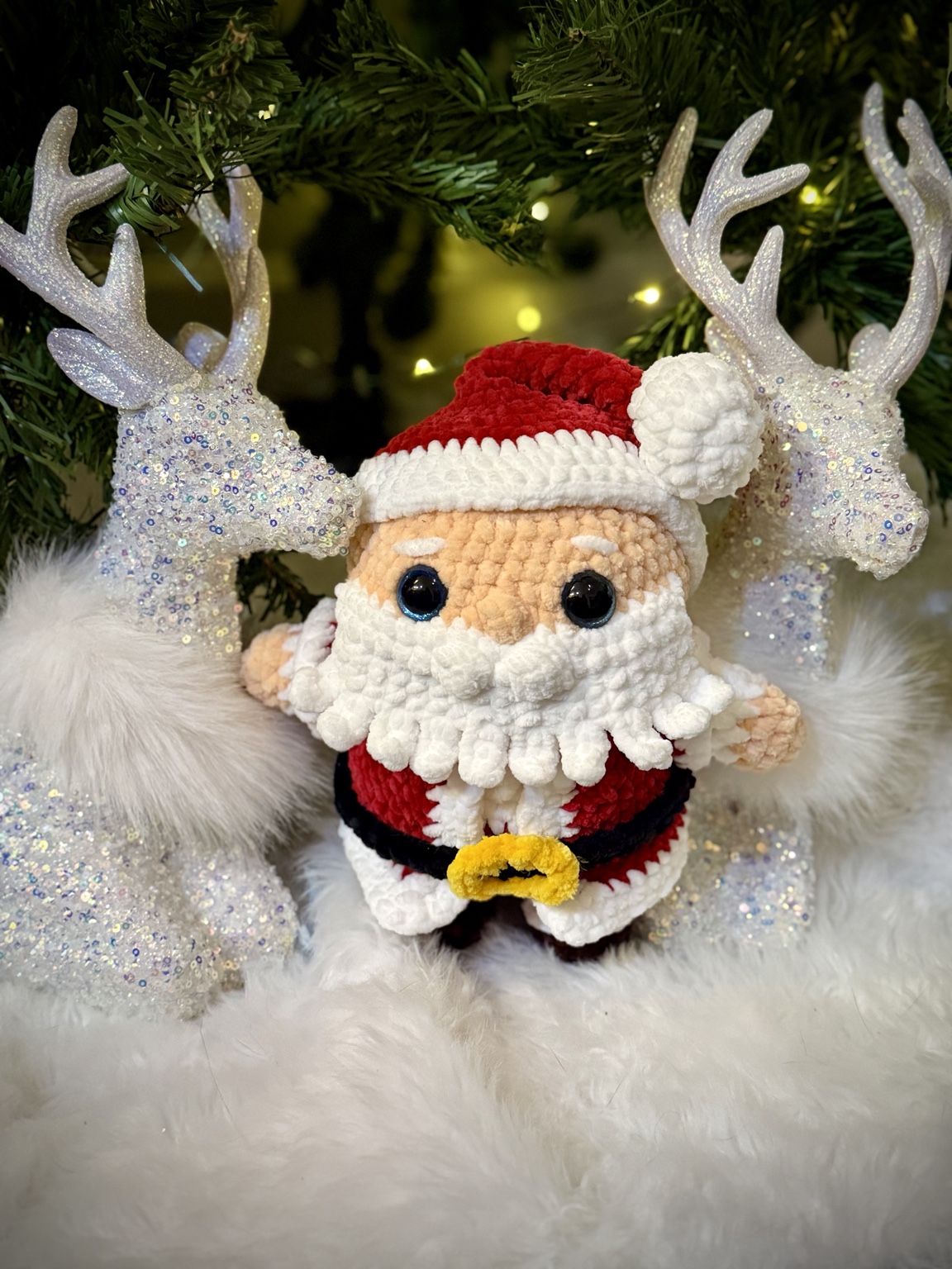 Crochet Santa with a white beard and red hat, beside decorative reindeer.