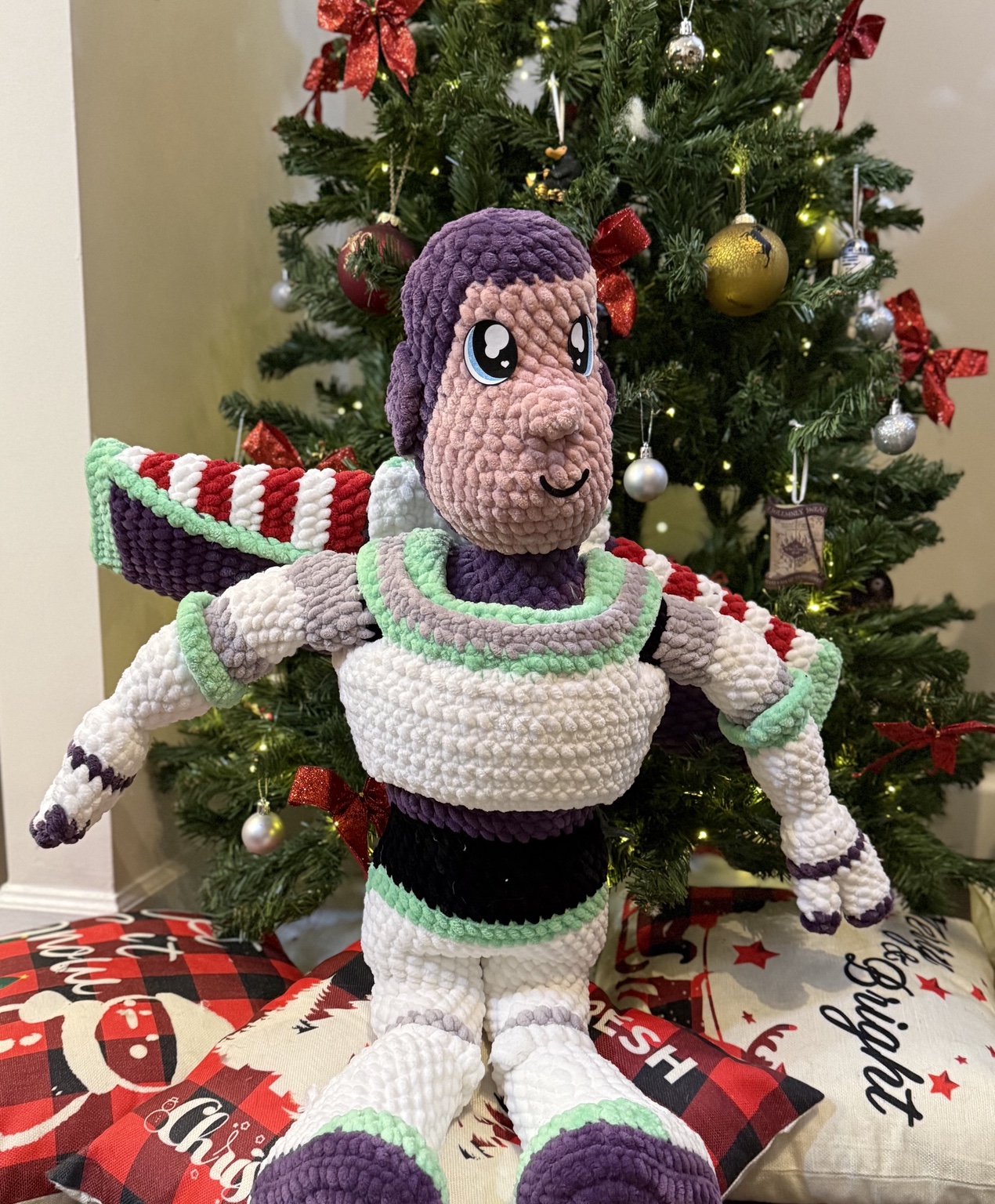 Large crochet space ranger in a white, green, and purple suit, in front of a Christmas tree.