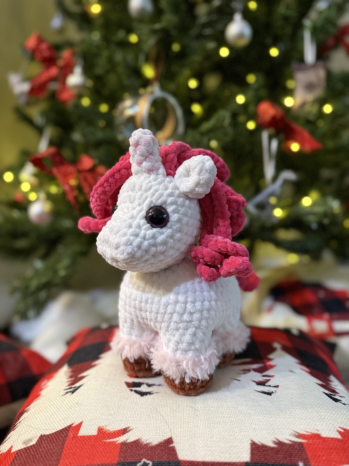 White crochet unicorn with a dark pink mane and brown hooves.
